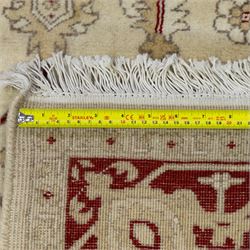 Baluchi signed hand-knotted rug, ivory ground, with an all-over geometric lattice design incorporating stylised flowerheads, hooked motifs and angular vine work, enclosed by a crimson border with repeating floral motifs and scrolling vines, flanked by narrow patterned guard stripes, signed to one corner, with cotton fringes
