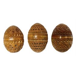 Three 19th century coquilla nut pomanders or flea catchers, each of egg shaped form with carved and pierced decoration and screw threaded join, largest example 6cm