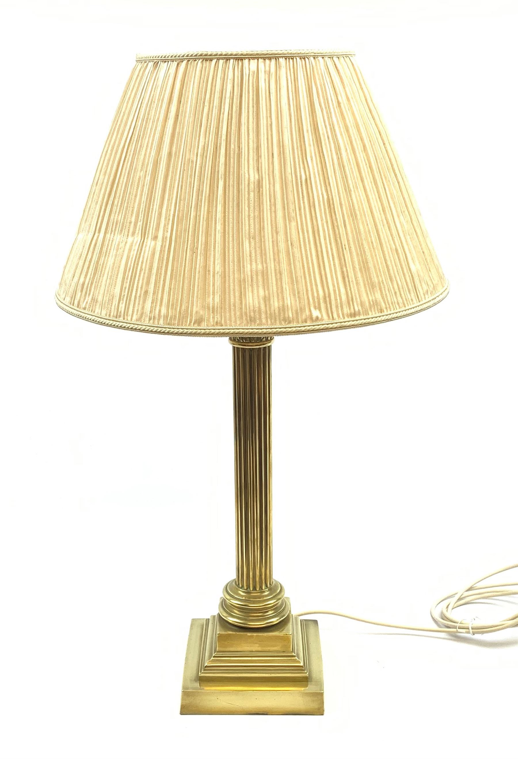 A brass Corinthian column table lamp, on stepped square base, including fitting H57cm, with pleated shade.