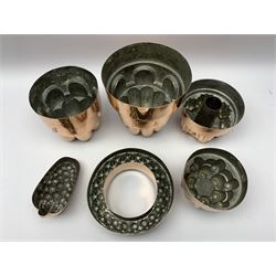 Six Victorian copper jelly moulds, five examples of castle type form, one example modelled as a bunch of grapes, largest H21cm