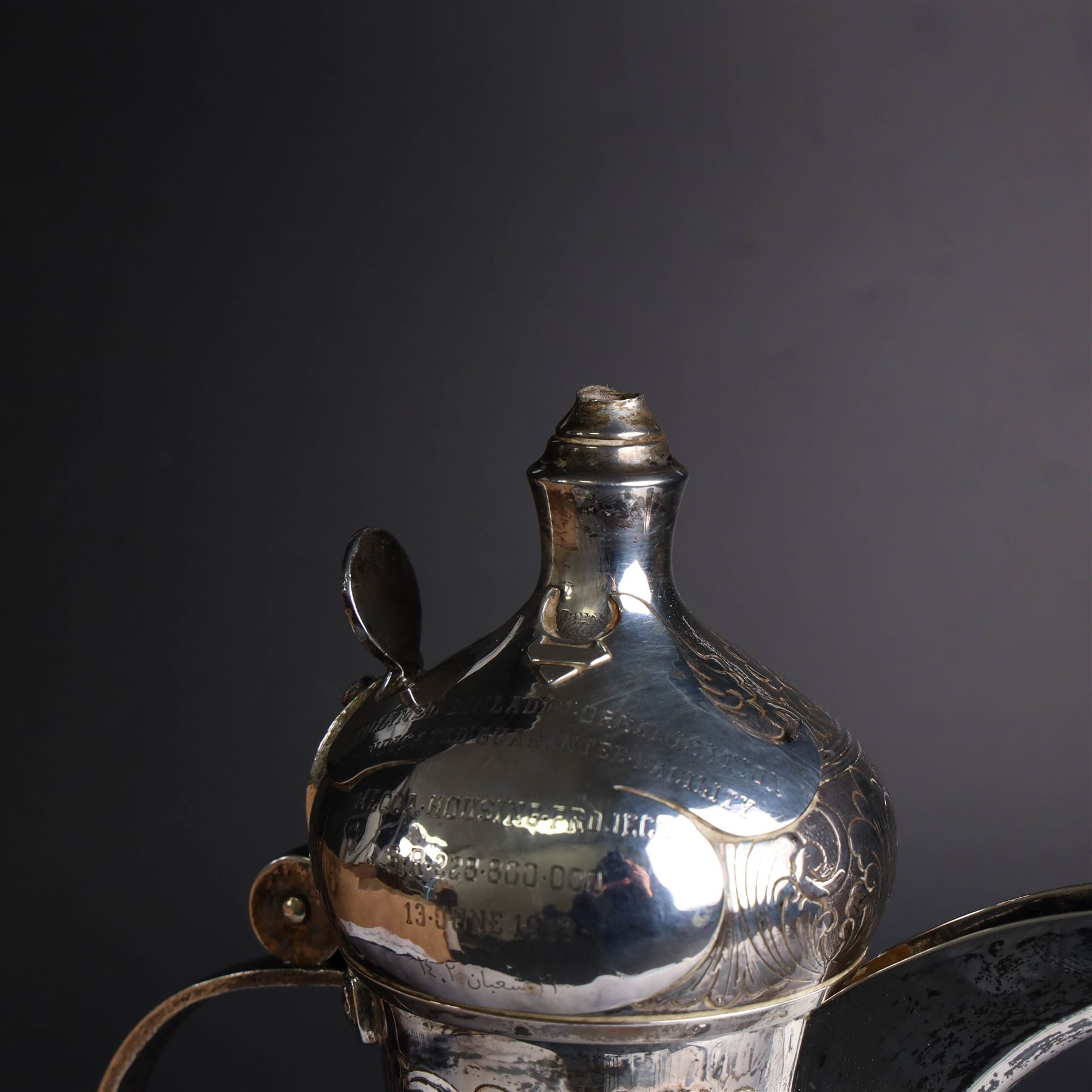 Middle Eastern silver coffee pot or Dallah, of baluster form with elongated spout and domed lid, with chased scrolling foliate decoration, the lid with applied silver plaque with presentation engraving, stamped 925 to base, H26.5cm