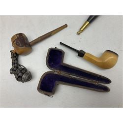 Swiss mountain hunters tobacco pipe with a horn mouthpiece, metal hinged pierced lid and brass chain, the black coated body adorned with small metal cow flowers, together with two other pipes and case, brass mounted horn, brass mounted bone box, carved mother of pearl handled knife and fork and brass jug