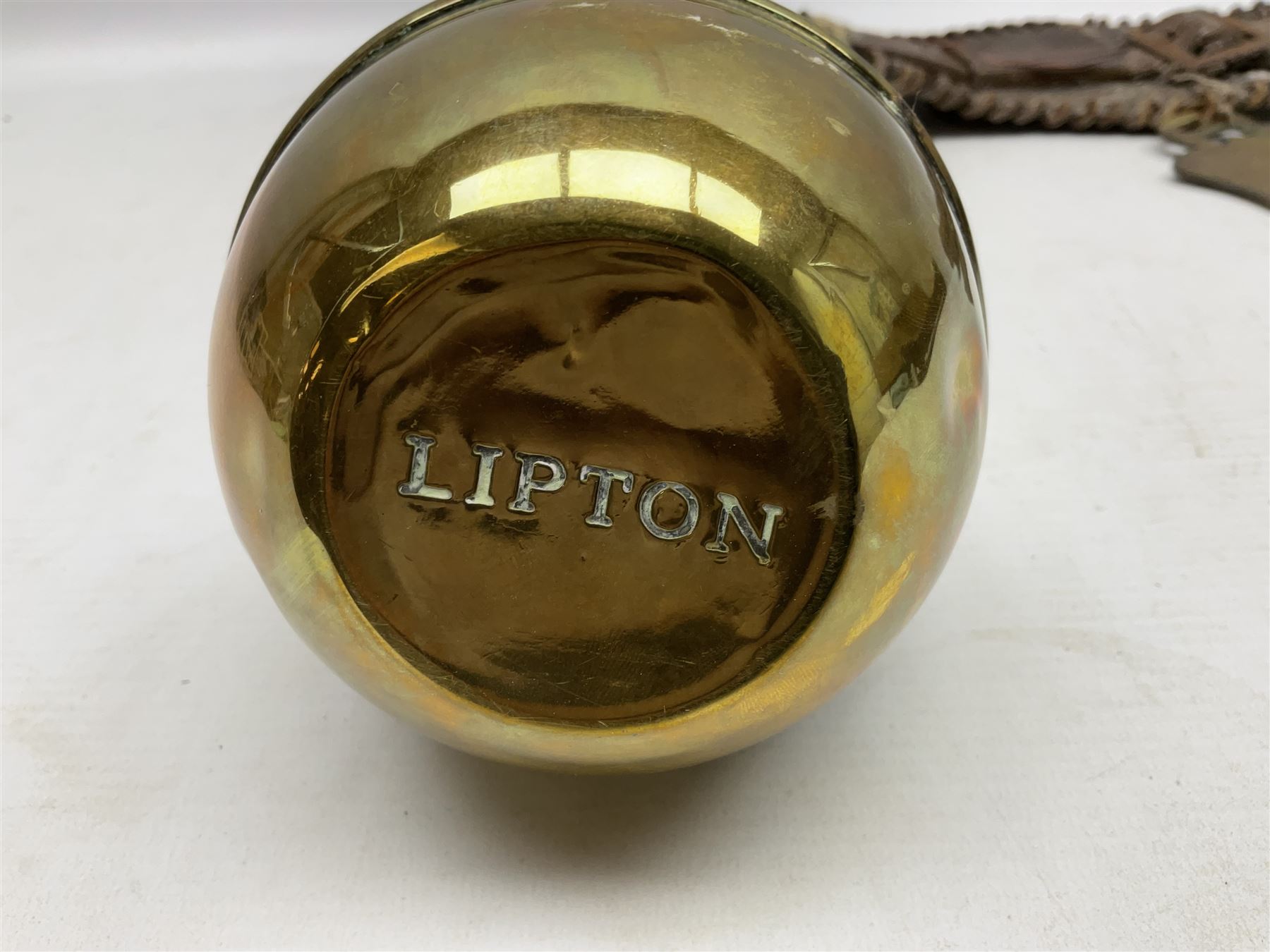 Victorian Queen Victoria record reign horse brass and H&SNCC Parade Badge of Merit 1911 horse brass, both on leather strap, together with 1924 British Empire Exhibition brass Lipton's souvenir tea caddy, strap L36cm