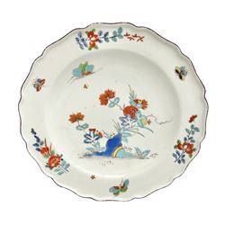 Mid 18th century Chelsea red anchor period plate, circa 1752-1754, hand painted in enamels in the Kakiemon palette with flowering peony and chrysanthemum issuing from rock work, and butterfly in flight above, the shaped rim detailed with conforming floral sprigs and butterflies within a iron red line border, with red anchor mark beneath, D22cm