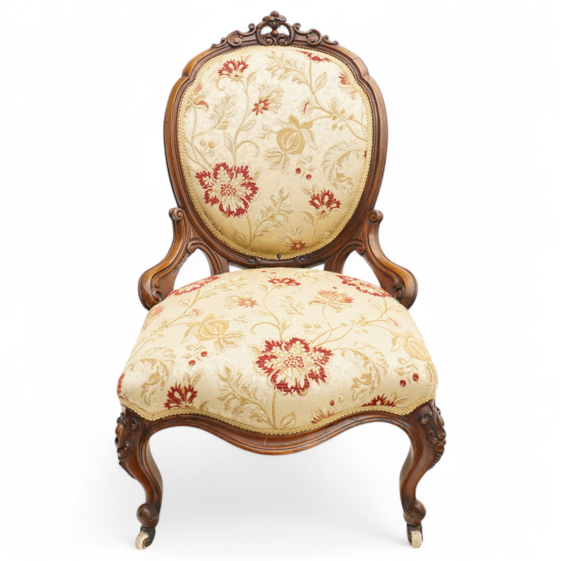 Victorian Ladies and Gentleman's carved walnut drawing room chairs, each with shaped cresting rail carved with scrolls and flowerheads, upholstered in pale gold floral fabric, raised on foliate-carved cabriole supports terminating to brass and ceramic castors