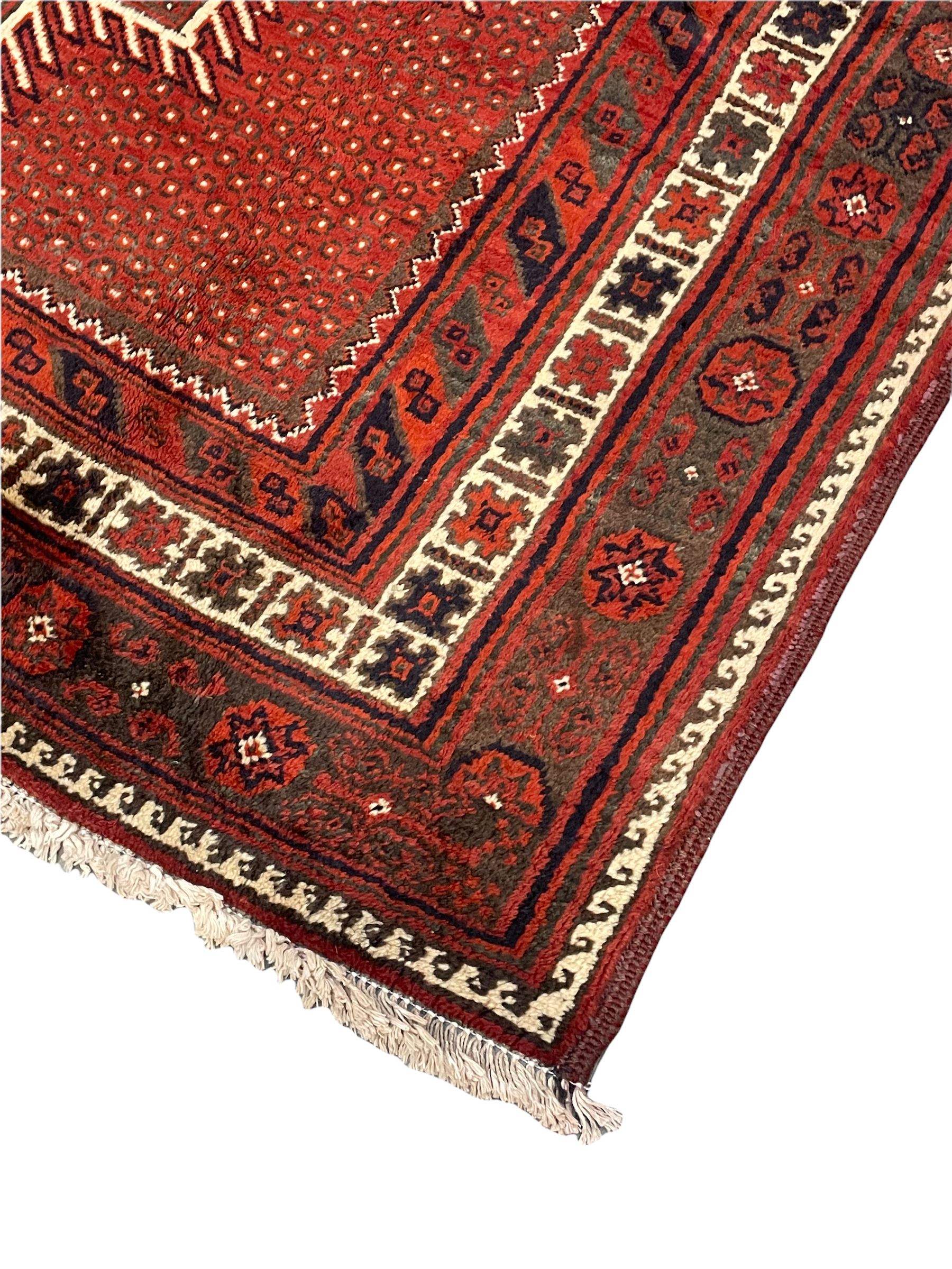 Persian Kelardasht red ground rug, the field decorated with two geometric medallions, multi-band border decorated with stylised flower heads and geometric repeating patterns