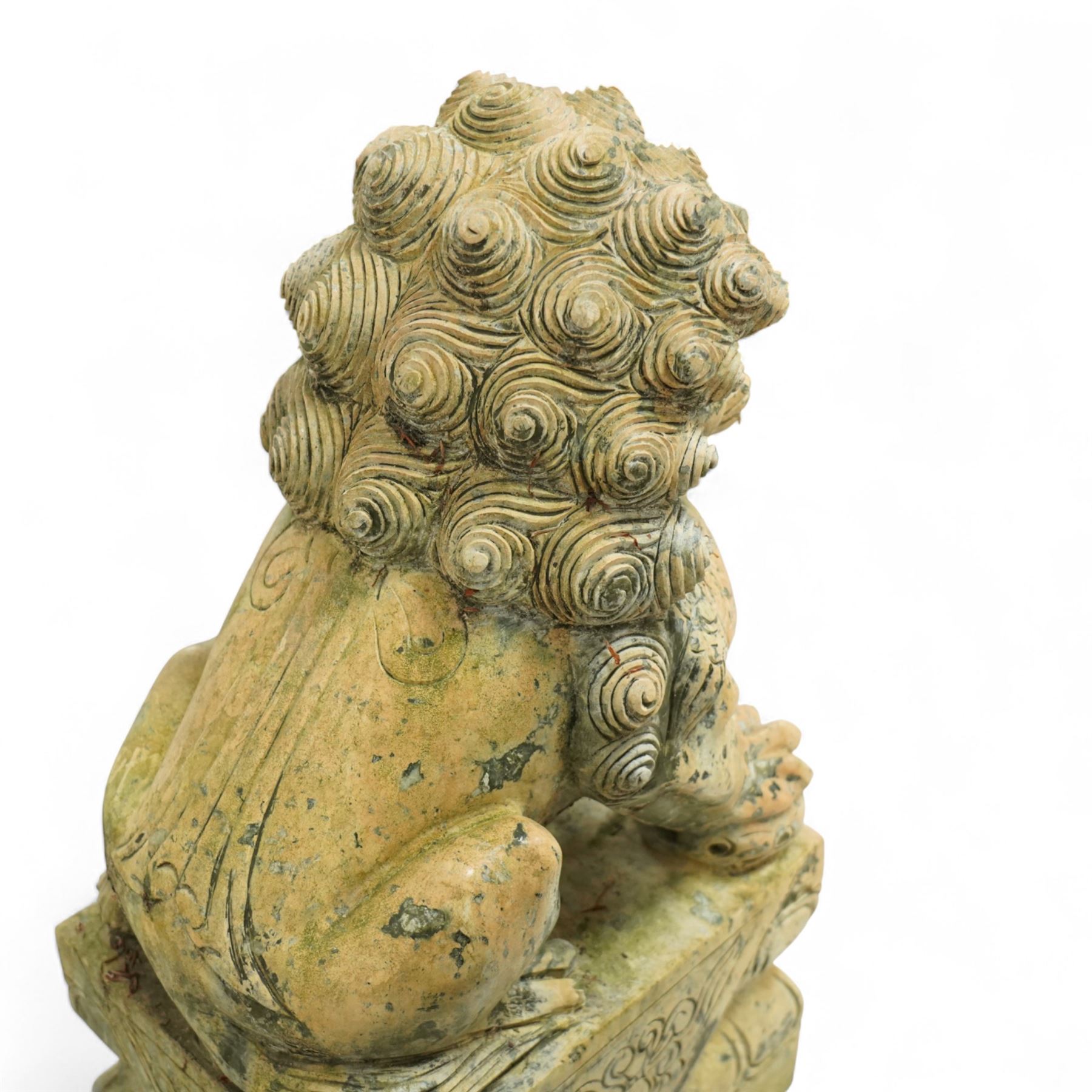 Pair of Chinese hardstone carved Foo dogs, each finely carved seated on rectangular plinth bases with detailed manes, collars and bells, the male with paw resting on a ball, the female with cub, in mottled green stone resembling jade