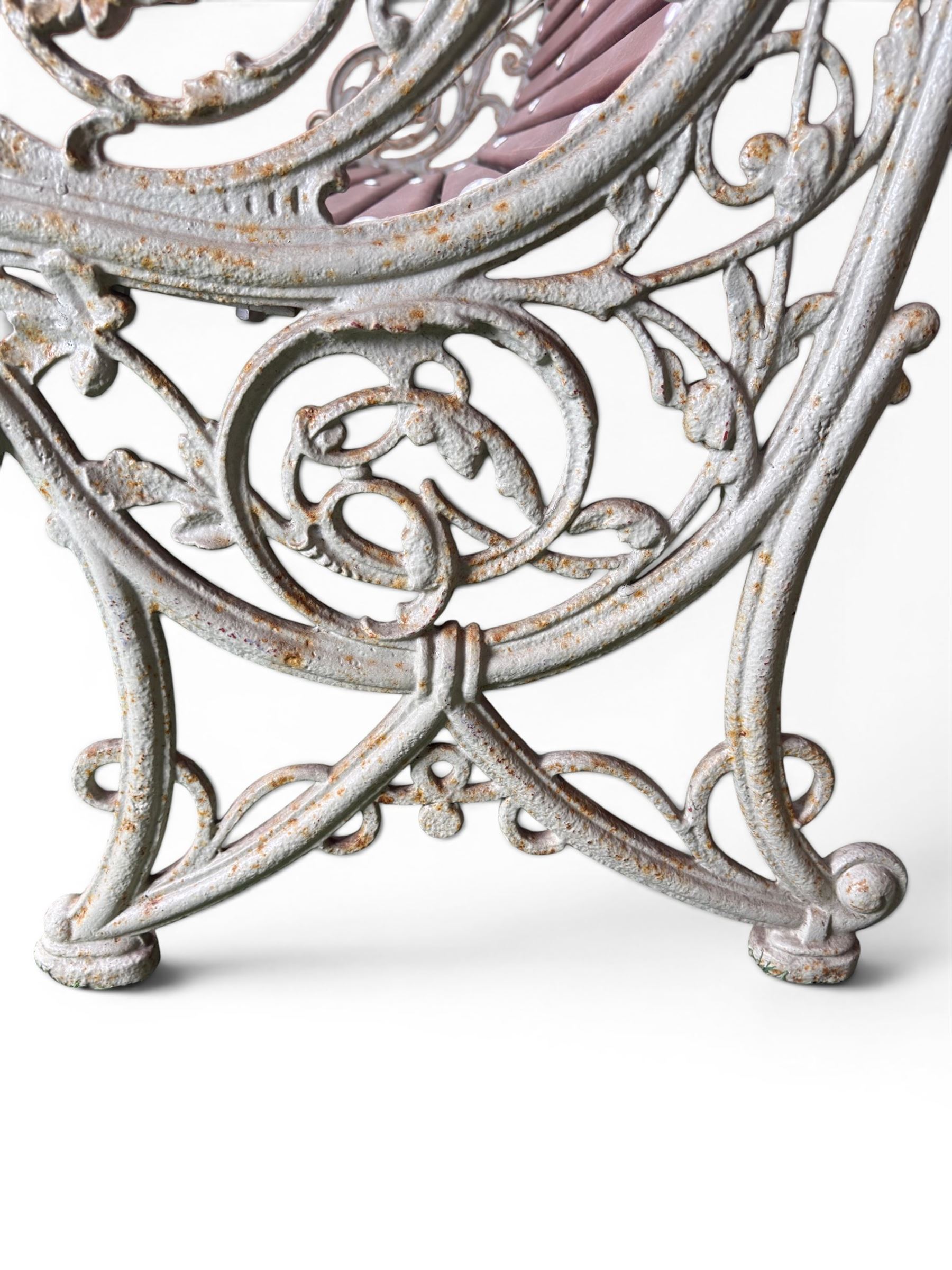 Large late Victorian cast iron garden bench, serpentine form with scroll back and seat, slatted with mahogany stained Sapele