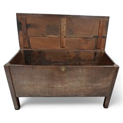 Large late 17th Century oak coffer, the hinged lid with twin rear strap hinges above a plain front with inset brass escutcheon, raised on square supports with pegged joinery and displaying pronounced grain figuring to the single front board