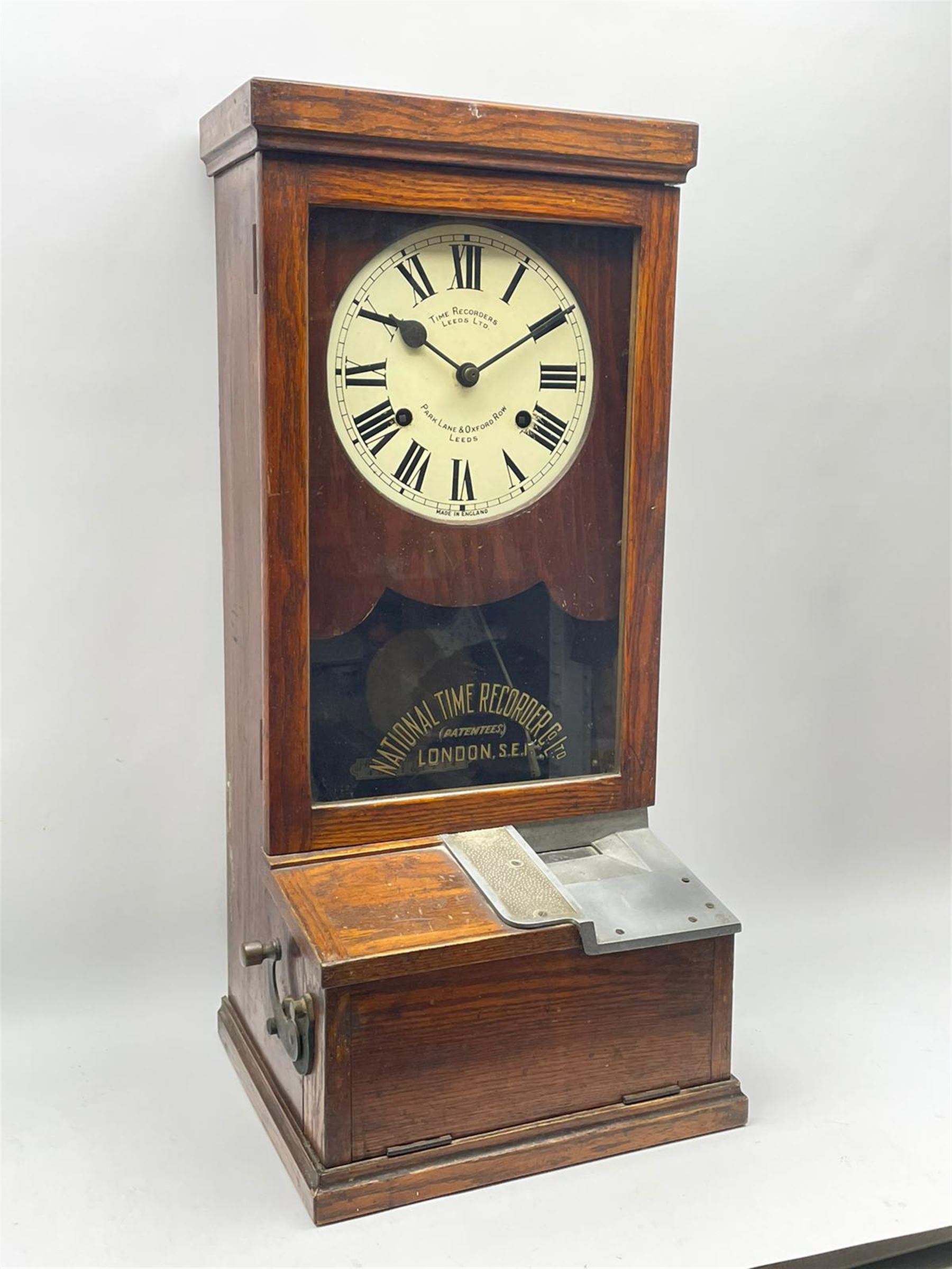 Early 20th century oak cased time recorder, circular Roman dial signed 'Time Recorders Leeds Ltd. Park Lane & Oxford Row Leeds', the glazed door signed 'National Time Recorder Co Ltd. London...'