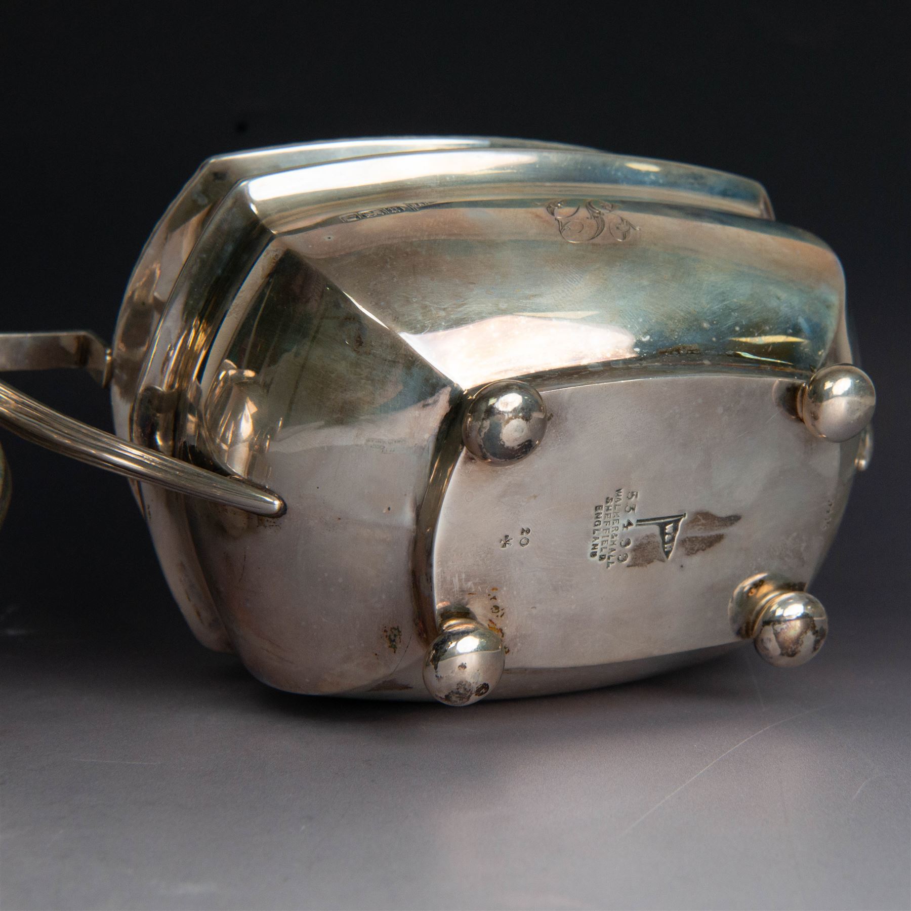 Early 20th century three piece silver tea service, comprising teapot, open sucrier and milk jug, all with oblique gadrooned rim, engraved initial to body and upon four bun feet, the teapot with Bakelite type handle and finial, hallmarked Walker & Hall, Sheffield 1912, contained within an oak presentation case with silk lining