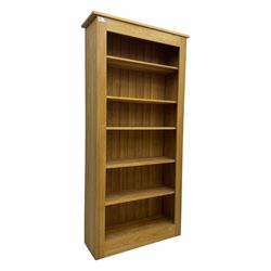 Contemporary light oak open bookcase, rectangular form with projecting top, fitted with five adjustable shelves, on a straight plinth base