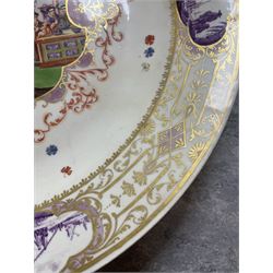 Large and impressive 18th century Meissen dish, finely painted with a chinoiserie scene to a central shaped reserve, depicting figures and attendants engaged in various pursuits, the reserve with gilt scrollwork edge, filled with Böttger lustre and detailed with iron red scrollwork, surrounded by flower heads, the rim with four quatrofoil Kauffahrtei scene panels of merchants and figures by a quayside in purple monochrome, with gilt scroll border, with under glazed blue crossed swords mark, and gilt gilders mark, D39cm
