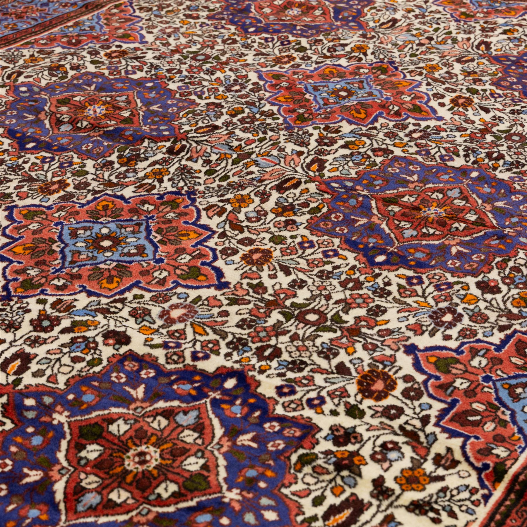 West Persian Hamadan hand-knotted rug, ivory field decorated with a repeating lattice of stylised geometric medallions interspersed with small floral motifs and angular vine ornament enclosed by a sky blue border of stylized rosettes and geometric devices between multiple guard stripes, with cotton fringe ends  