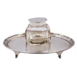 1920's silver ink stand, of oval form with reeded rim, and removable faceted glass inkwell with hinged silver mounted cover, the stand upon four splayed feet, hallmarked William Neale & Son Ltd, Birmingham 1924, W13cm, stand (without inkwell) approximately 1.63 ozt (50.6 grams)