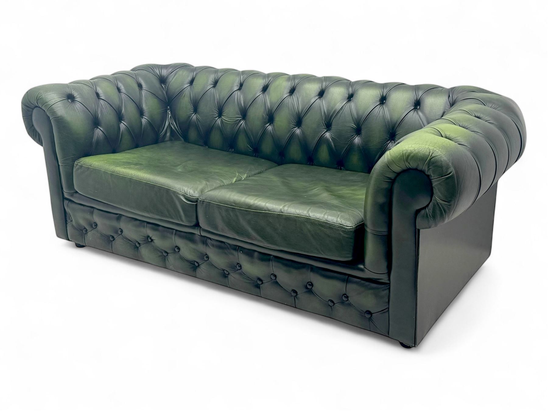 Two seat Chesterfield design sofa bed, upholstered in emerald green leather with deep-buttoned detailing, rolled arms, two loose seat cushions, and pull-out 