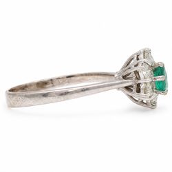 White gold emerald and diamond cluster ring, single oval cut emerald of approx 0.25 carat, surrounded by six round brilliant cut diamonds, stamped, total diamond weight approx 0.30 carat