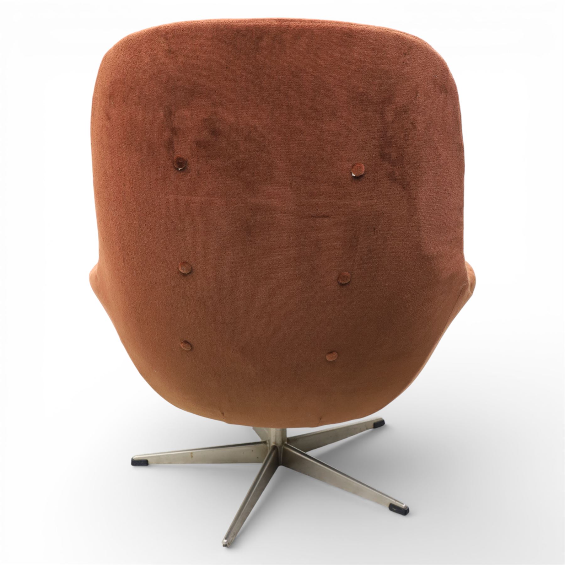 Pair of mid 20th century brown velvet swivel lounge chairs and matching footstool, the shaped and padded back with buttoned segmented cushion over conforming seat cushion, flared armrests and moulded sides, raised on a five point metal swivel base, the footstool en suite with buttoned cushion and matching metal base