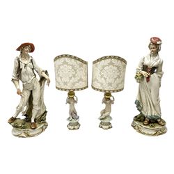 Pair of Capodimonte table lamps, in the form of cherubs holding a brass fitting, together with a pair of large Capodimonte figures in the form or a man and woman resting up on tree stump, largest example H57cm