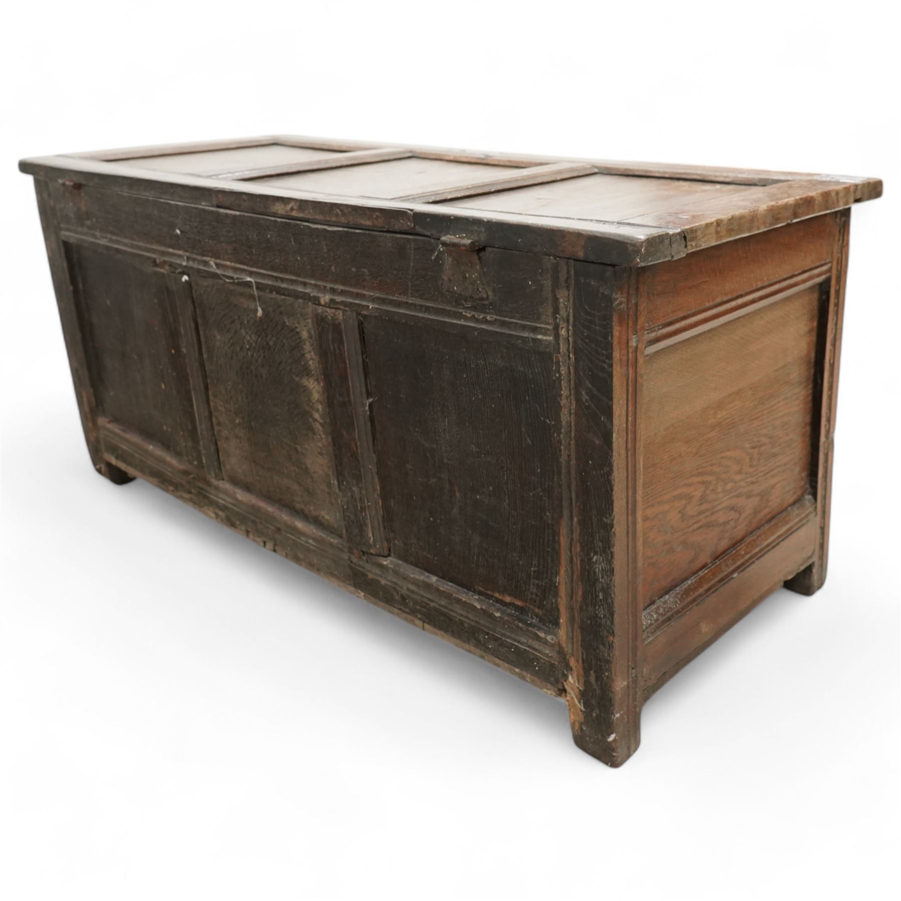 18th century oak coffer or blanket box, triple panel hinged lid over panelled front and sides, the front carved with scrolling foliate motifs and lozenges, moulded frame with chip carved decoration on stile supports 