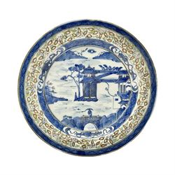 Late 19th century Chinese rice plate, of circular form decorated with underglaze blue landscape featuring figure on bridge before pagodas, heightened with gilt and contained within blue diaper borders and foliate polychrome enamel border, with Guangxu six character mark beneath, D21cm