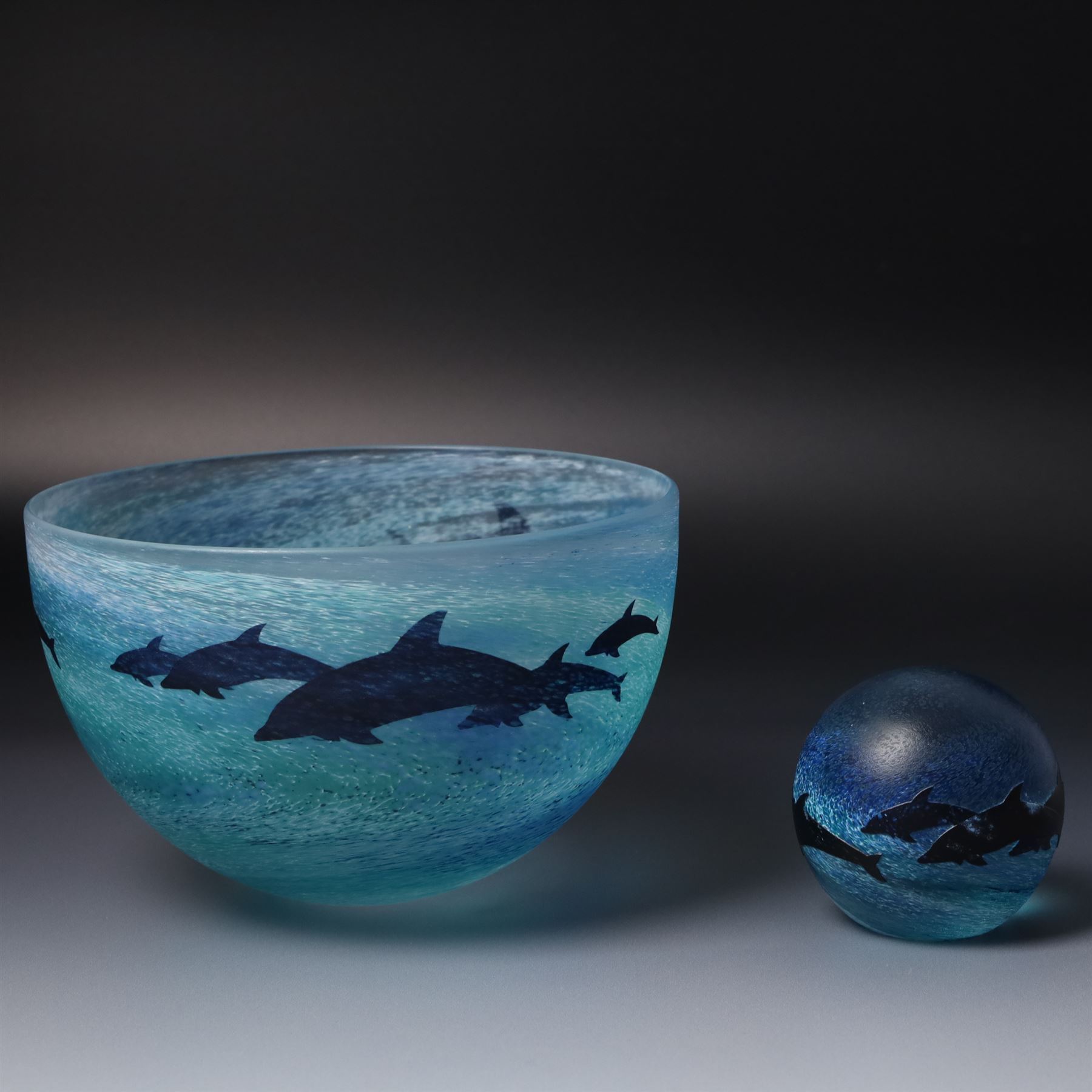 Malcolm Sutcliffe (British 1954-): Studio glass cameo bowl, the body mottled and speckled with shades of blue decorated with dolphins, etched signature, D18cm and matching paperweight (2)