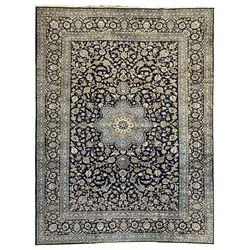 Central Persian Kashan indigo ground carpet, central lighter blue floral medallion surrounded by interlacing leafy branches and stylised plant motifs, the main border decorated with repeating floral motifs and scrolling branches, within guard stripes 