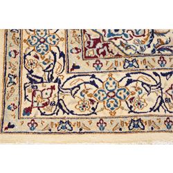 Persian Nain ivory ground rug, the busy oval field profusely decorated with scrolling foliate decoration and palmettes in citrine and indigo tones, the central medallion with matching spandrels, the multiple guard bands with repeating stylised quatrefoil motifs and trailing scrolling foliage and flowerheads