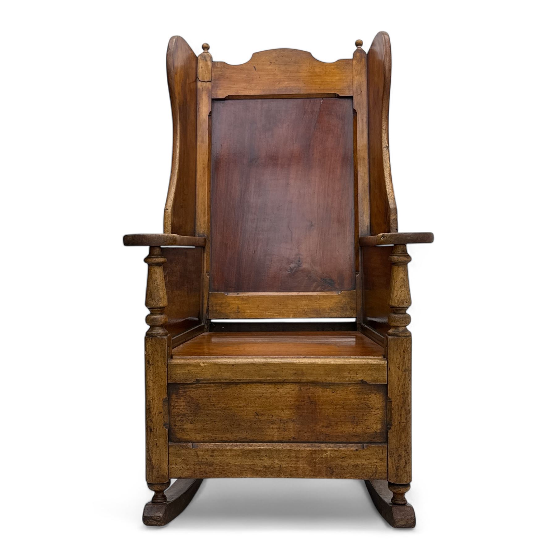 19th-century beech, yew, elm, and mahogany wingback vernacular rocking chair, high back with shaped wings, scroll arms with turned supports, lift-up seat,  square legs on ring turned supports on curved runners 