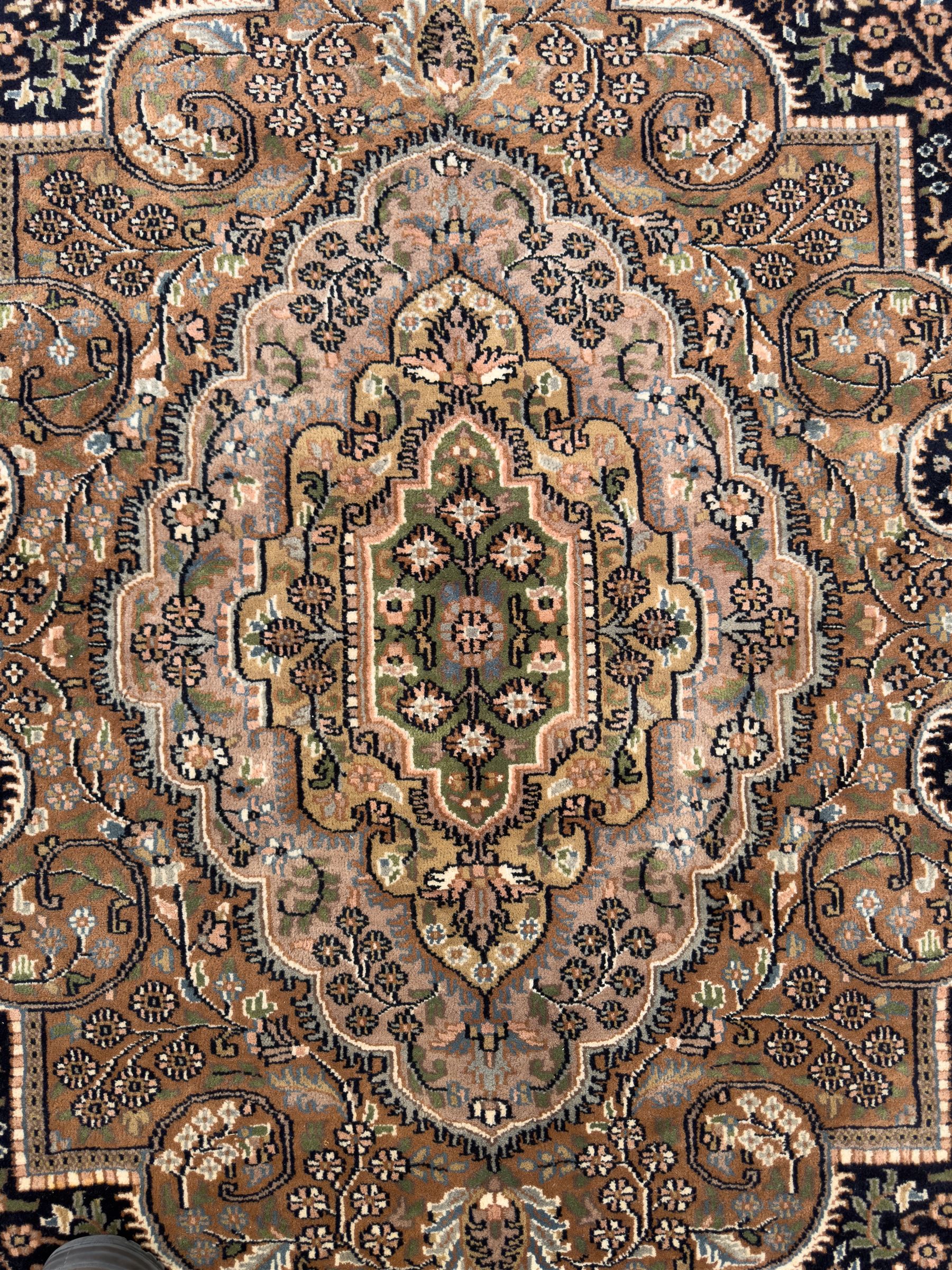 Large Persian indigo ground rug, the busy field decorated with trailing branches and flower heads, peach border decorated with palmettes -