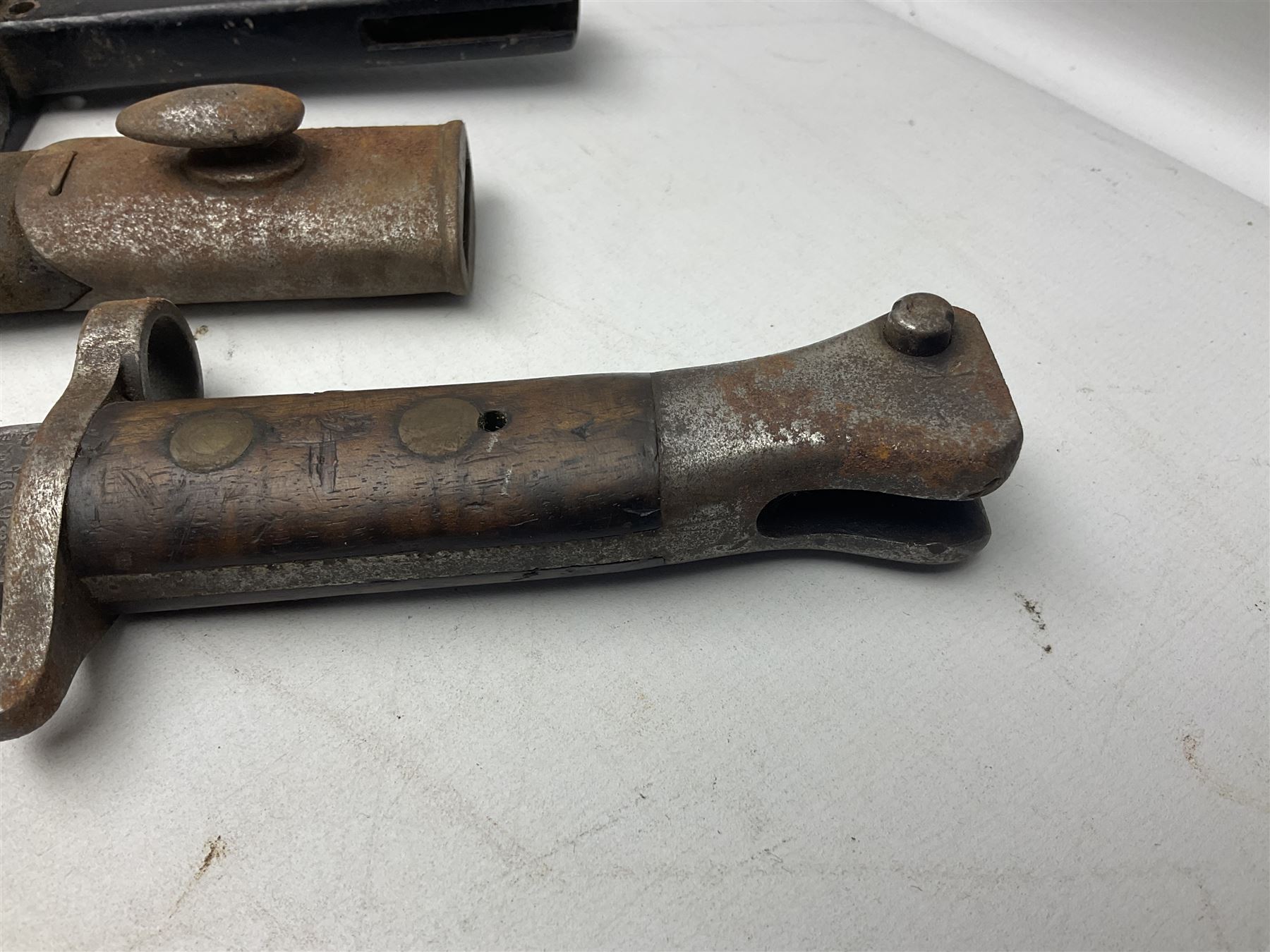 British No 7 MKI knife bayonet with 20cm single edged fullered clipped point blade;  blackened steel, large muzzle ring cross-guard; blackened swivelling pommel marked 'F5H'; red Tufnol composite grips; in blackened steel scabbard L33cm overall; British Pattern 1888 bayonet with scabbard; and German Ersatz bayonet with scabbard (3)