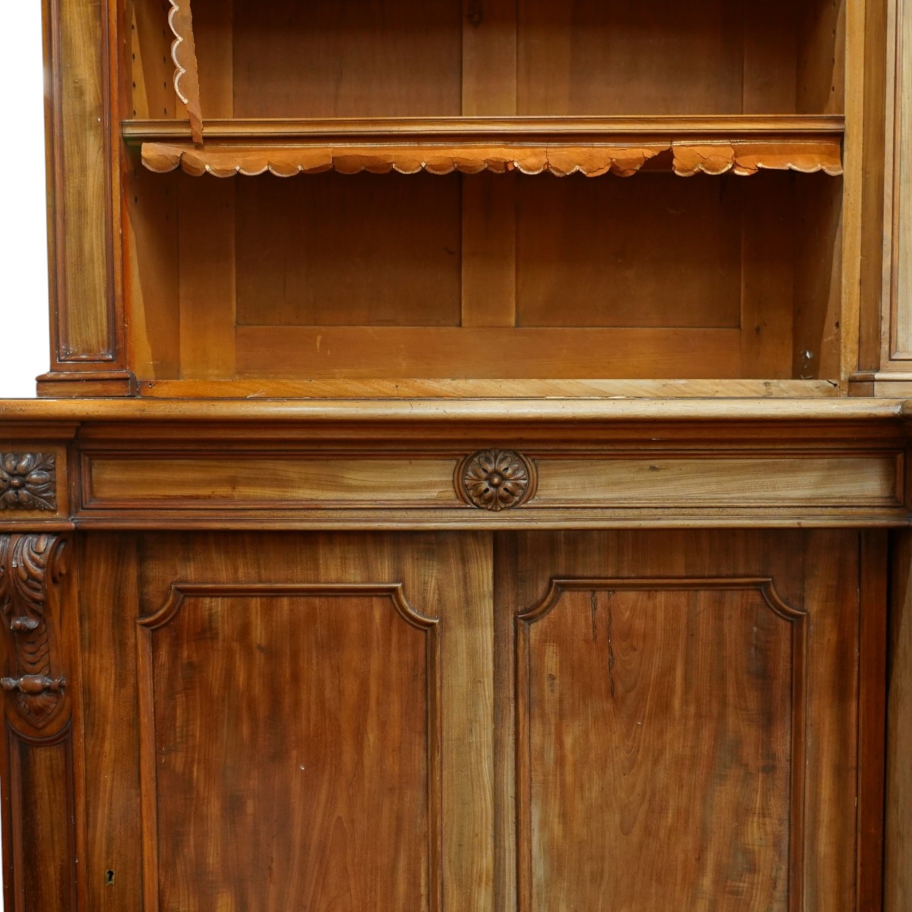 Large early 19th century Country House mahogany breakfront library bookcase, the projecting moulded cornice over a frieze applied with carved flowerhead paterae, the open panelled upper section fitted with adjustable shelves and shaped valances, divided by moulded pilasters with acanthus-carved corbels, the projecting base enclosed by eight panelled cupboard doors with central turned canted pilaster, on plinth base