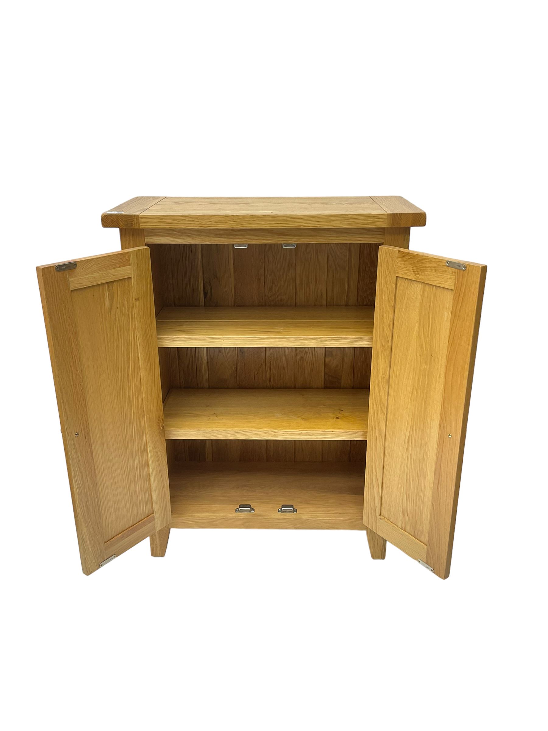 Solid light oak cupboard, fitted with two panelled doors enclosing two shelves, on tapered feet