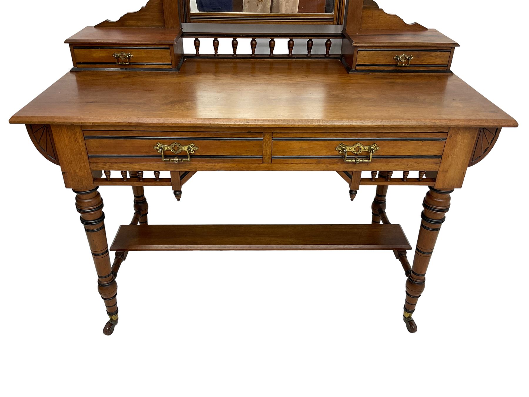 Late Victorian Aesthetic Movement walnut and inlaid ebony dressing table, swing mirror back with shell carving and spindle support rail, fitted with two trinket drawers and single frieze drawer, raised on ring turned supports with castors