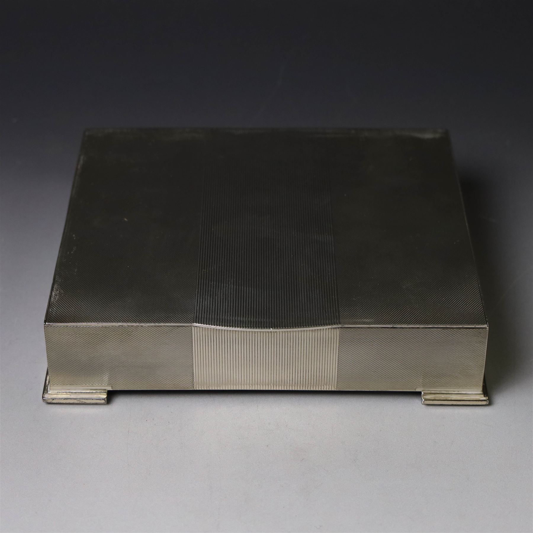 1960s silver mounted cigarette box, of rectangular form with engine turned decoration, upon four bracket feet, with presentation engraving to interior lid reading  'British Aircraft Corporation (Operating) Limited Commemorating the Queen's Award to Industry 1967, hallmarked James Geraghty, Birmingham 1965, with retailers mark for Asprey, W16.5cm, H4.5cm, in Garrard & Co Jewellers box