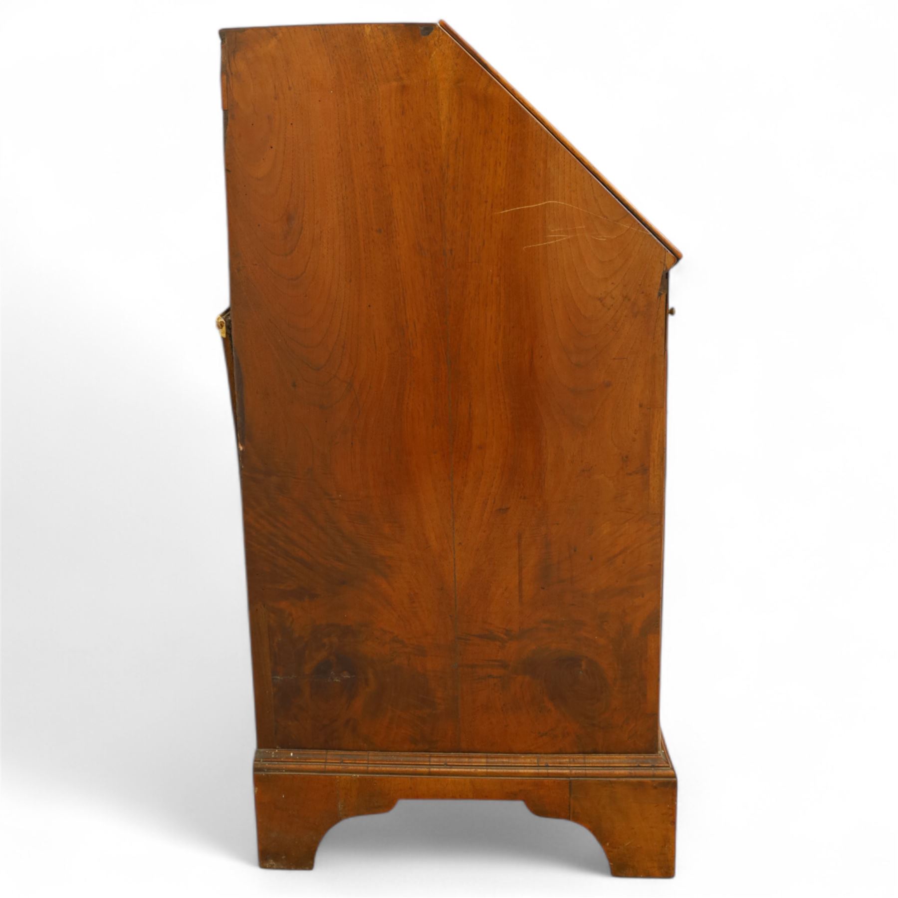 18th century walnut and herringbone banded bureau, the fall front enclosing a stepped and arched interior fitted with pigeonholes, drawers and concealed compartments, green tooled leather writing surface, over two short and three long graduated drawers with brass escutcheons and bail handles, shaped bracket feet