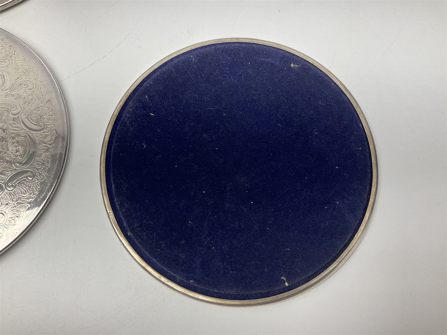 Set of eight silver plated placemats, each of circular form with engraved scroll and floral decoration, including two larger and six smaller examples, largest D23cm, in fitted case 