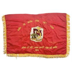 1960s North Vietnam banner embroidered in yellow thread on a red ground, roughly translates as 'Peoples Army of Viet Nam. Warriors of Viet Nam Determined To Keep The Country 1964' around a central military crest with the motto 'Warriors Keep The Country'; tassels to three sides 70 x 100cm