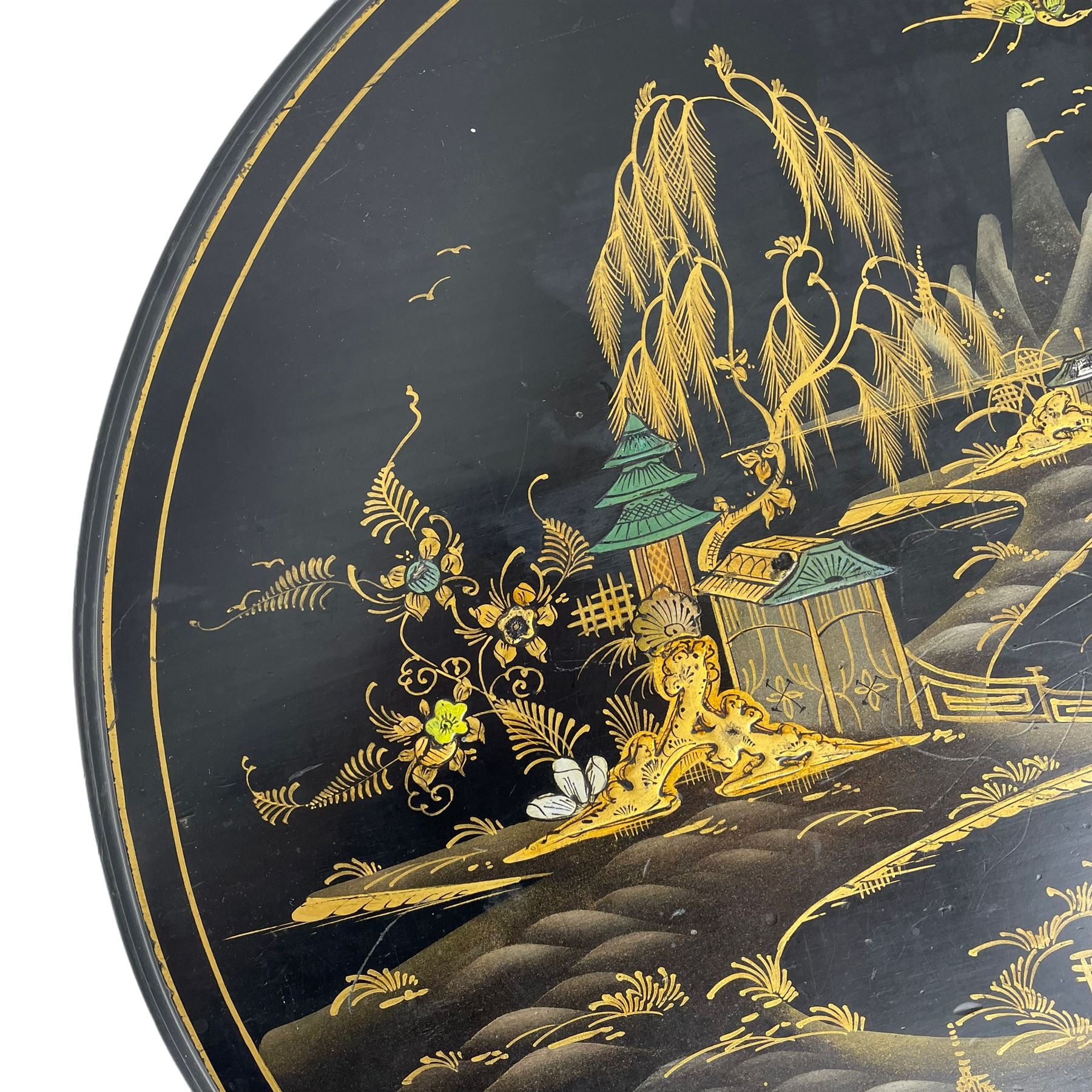 Early 20th century Chinoiserie lacquered circular occasional table, raised gilt decoration depicting traditional landscape scenes, on cabriole supports