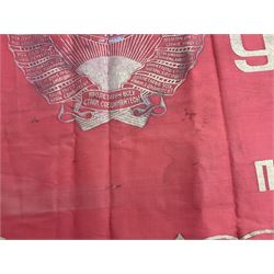 1970s Soviet banner printed in gold on a red ground, roughly translates as 'Transferable Banner - To the winner in the Socialist Competition' and 'Work Study Live by Communism' verso; wreath of wheat ears to either side; tassels on three sides 110 x 155cm