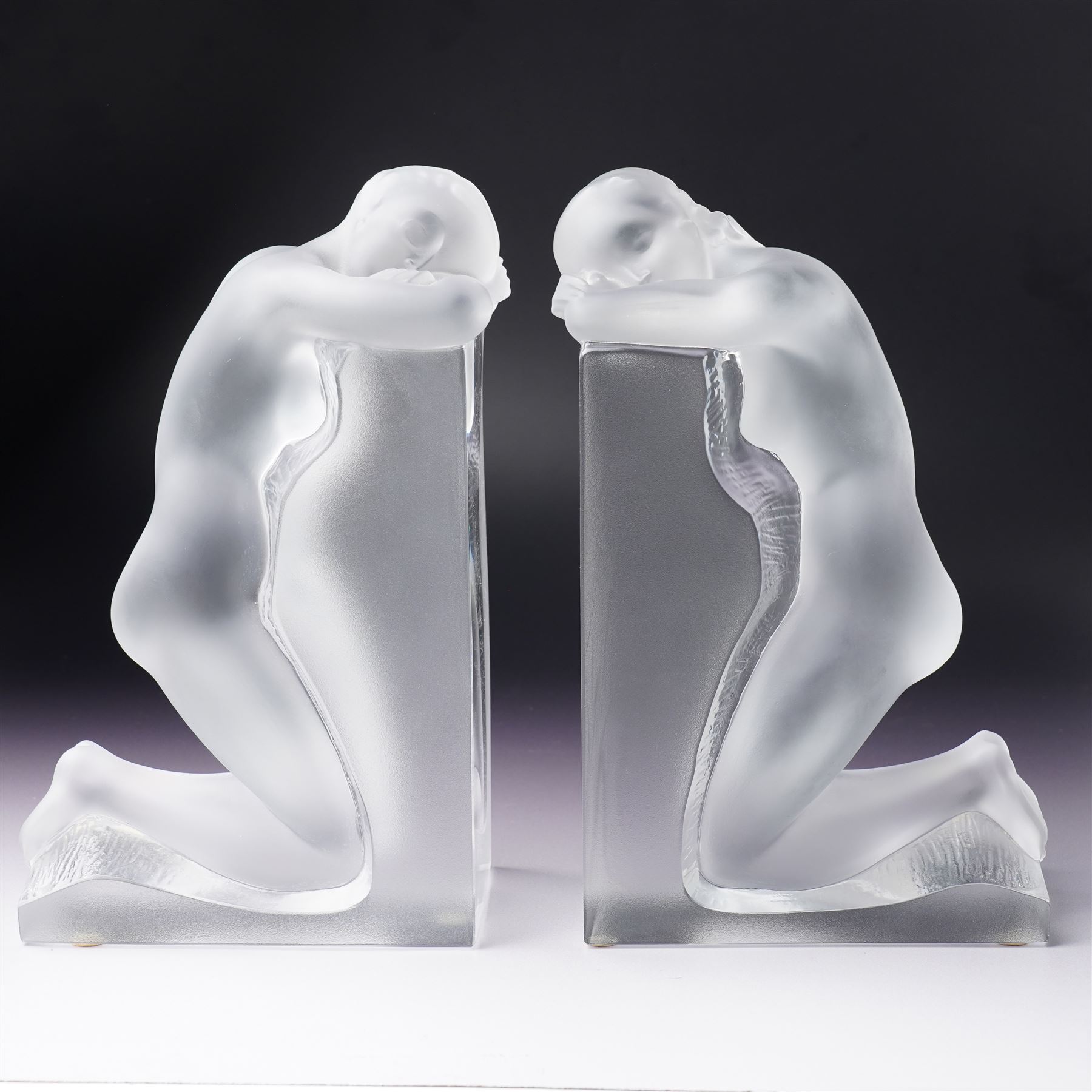 Pair of Lalique 'Reverie' glass bookends formed as two kneeling nude figures in clear and frosted glass inscribed 'Lalique France' to the plinth base H23cm
