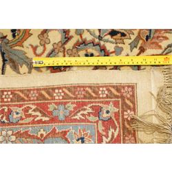 Persian Isfahan ivory and crimson ground rug, the busy field with central floral pole medallion surrounded by foliate motifs and stylised palmettes, the indigo guard line with repeating scrolling plant motifs