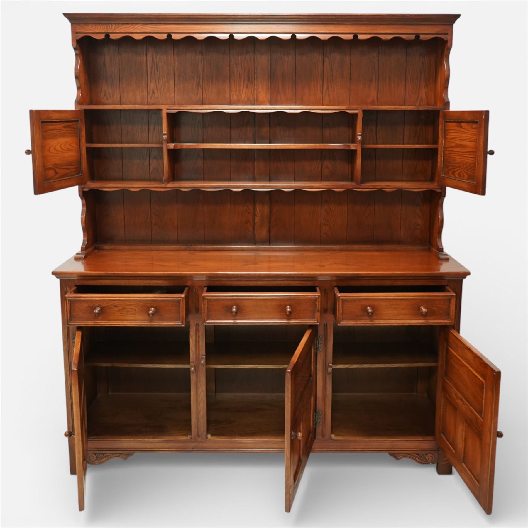 20th century oak dresser, moulded cornice above open plate rack with shaped frieze, flanked by two cupboard doors enclosing shelving, the base fitted with three drawers over three fielded panel cupboard doors, raised on bracket feet