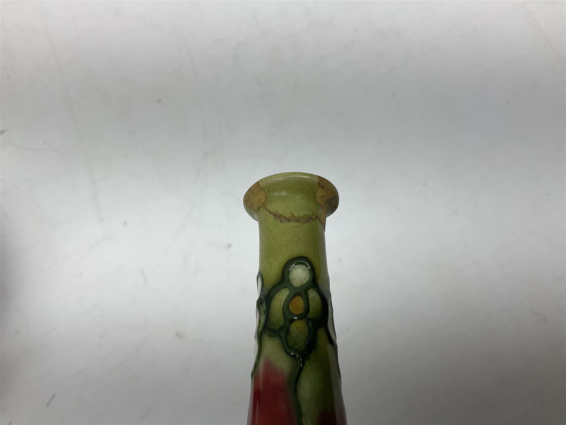 Three Minton Secessionist vases, with tube-lined stylised flower decoration, two upon a red ground and third upon a purple ground, all with printed mark to base 'Minton Ltd, No. 33', H13cm