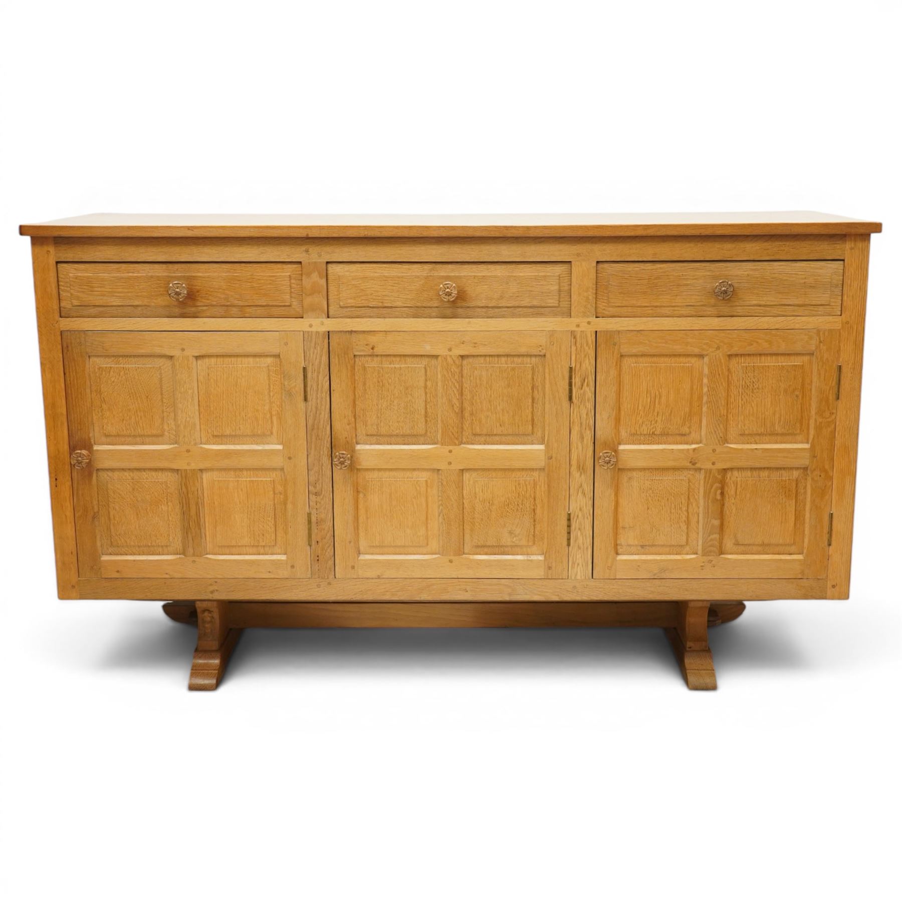 Beaverman - 1980s adzed oak sideboard raised on a trestle base, three drawers over three cupboards with Yorkshire Rose carved handles, fielded panelled sides and front, with carved Beaver, by Colin Almack of Sutton near Thirsk