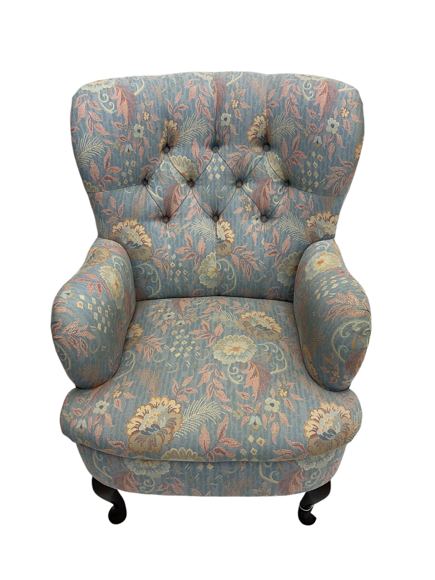 Mid-20th century wingback armchair, upholstered in soft blue floral patterned fabric with button-tufted backrest and curved arms and raised on cabriole supports