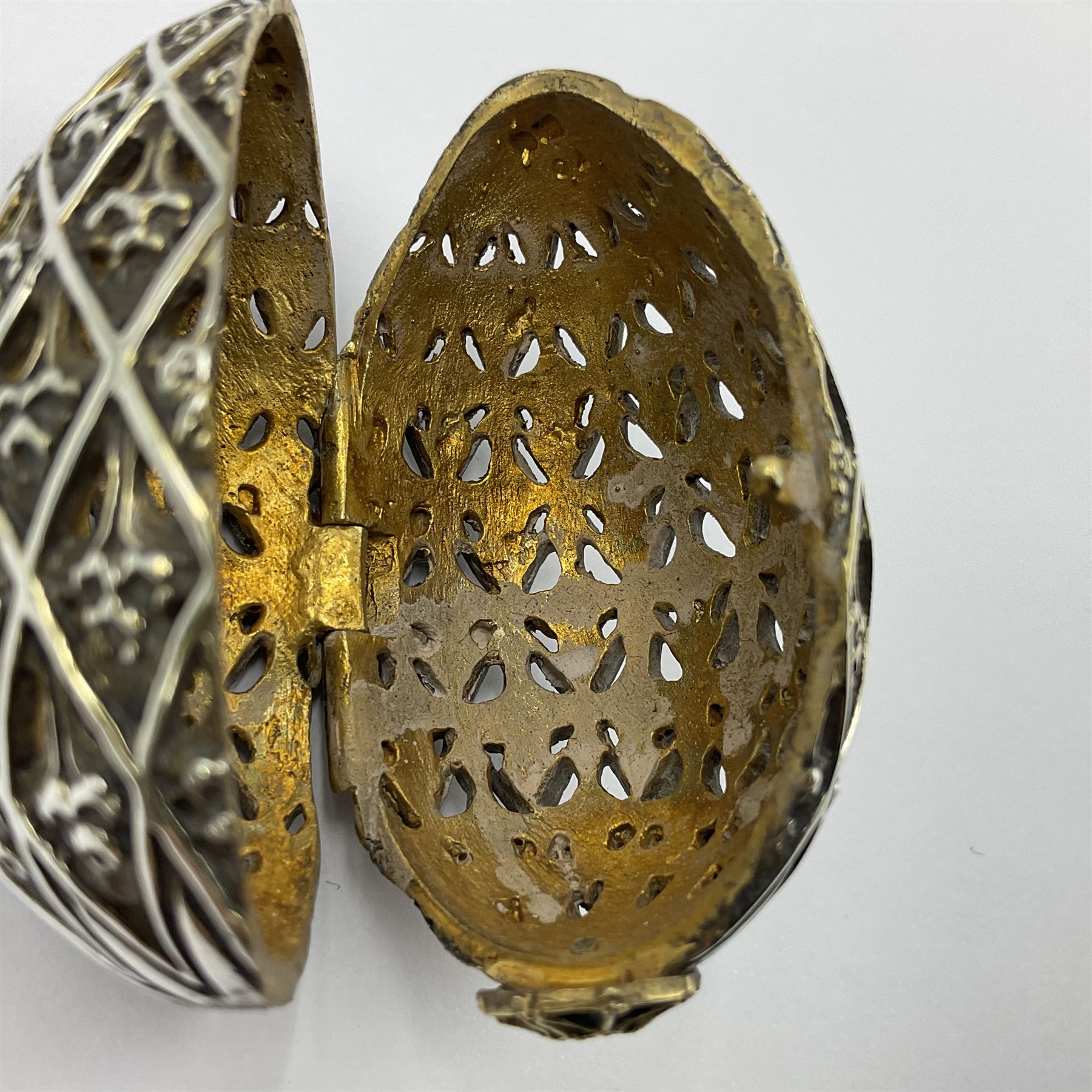 Modern silver limited edition Easter egg, no. 70/500, the openwork lattice body decorated with gilded panels of flower heads, opening to reveal a gilt interior, upon silver stand with three scrolling pad feet, each hallmarked St James House Company, London 1979, height including stand 8cm