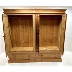 Large solid pine wardrobe, projecting cornice, four doors enclosing hanging rails above two drawers, platform base