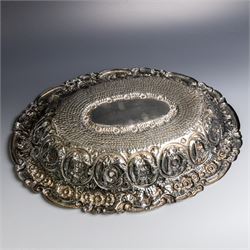 Late 19th/early 20th century continental silver serving bowl, of oval form, profusely embossed with scrolling floral and foliate decoration, with hammered finish to interior