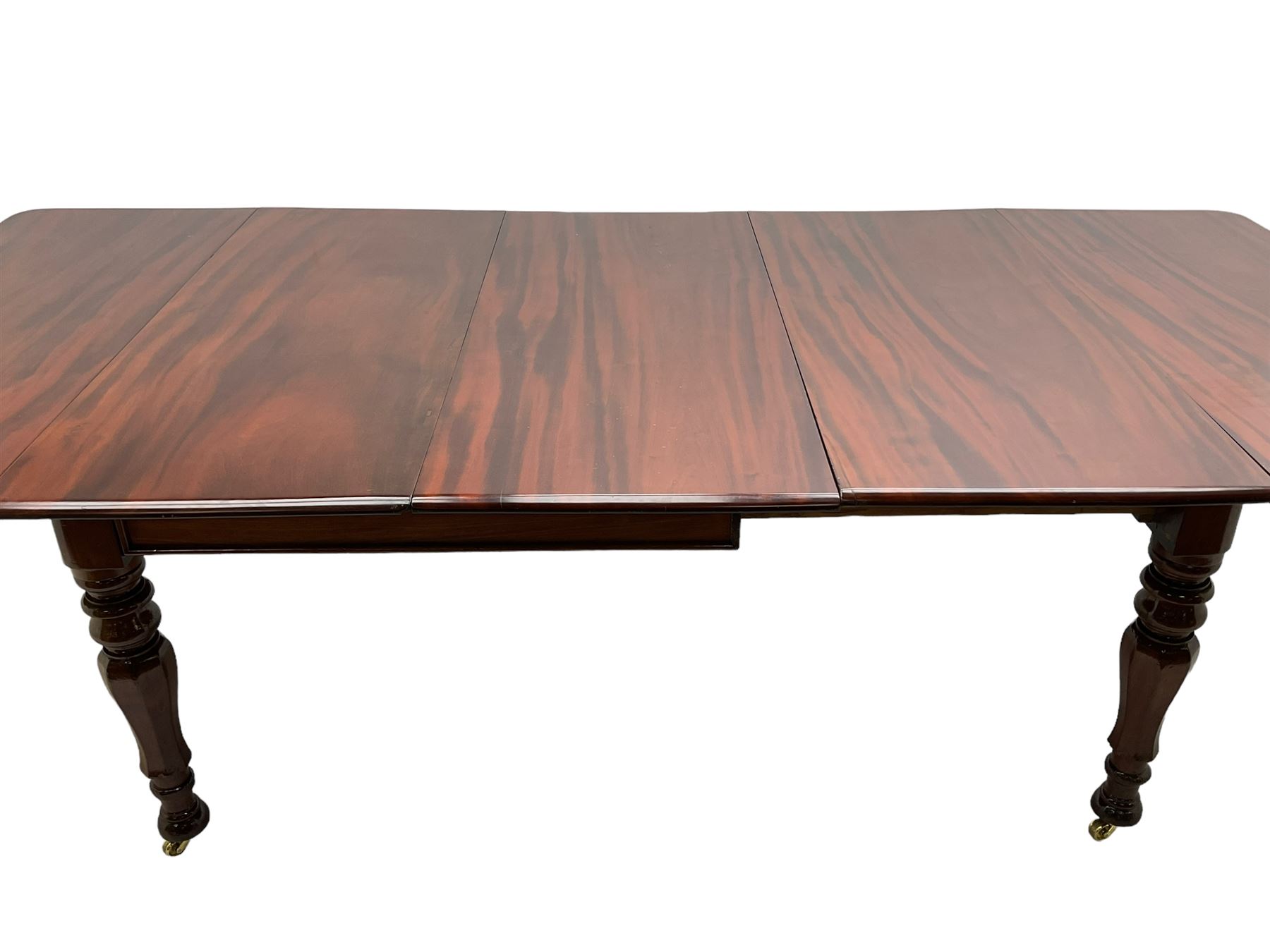 19th century mahogany extending dining table with three additional leaves, rectangular top with rounded corners, pull-out action, on turned and faceted supports with brass castors
